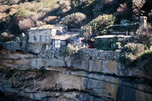 The stone huts at the eastern end of the Crater Cove settlement are substantial buildings high above the rock platform and waters of the cove.