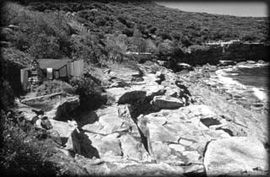 The view eastward along the rocky shorline of Crater Cove reveals the Men's hut.