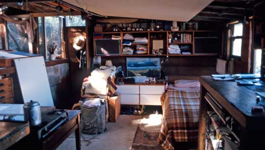 The simple needs of life are demonstrated in this interior image of Simon Flynn's shack in 1987. Note the artwork depicting a view over the harbour.
