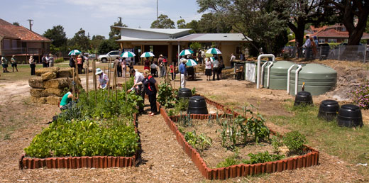 CPCG_opening_site The strawale classroom in its setting, with the old bowling club building (now used by Council's childcare centre and a community services agency) in the background left, the community garden's water tanks on the right and some of the shared garden beds in the foreground.